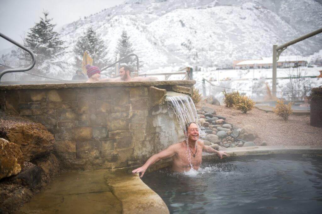 Man relaxing under waterfall at Iron Mountain Hot Springs in winter