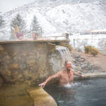 man in waterfall during winter time at ironmountain hot springs