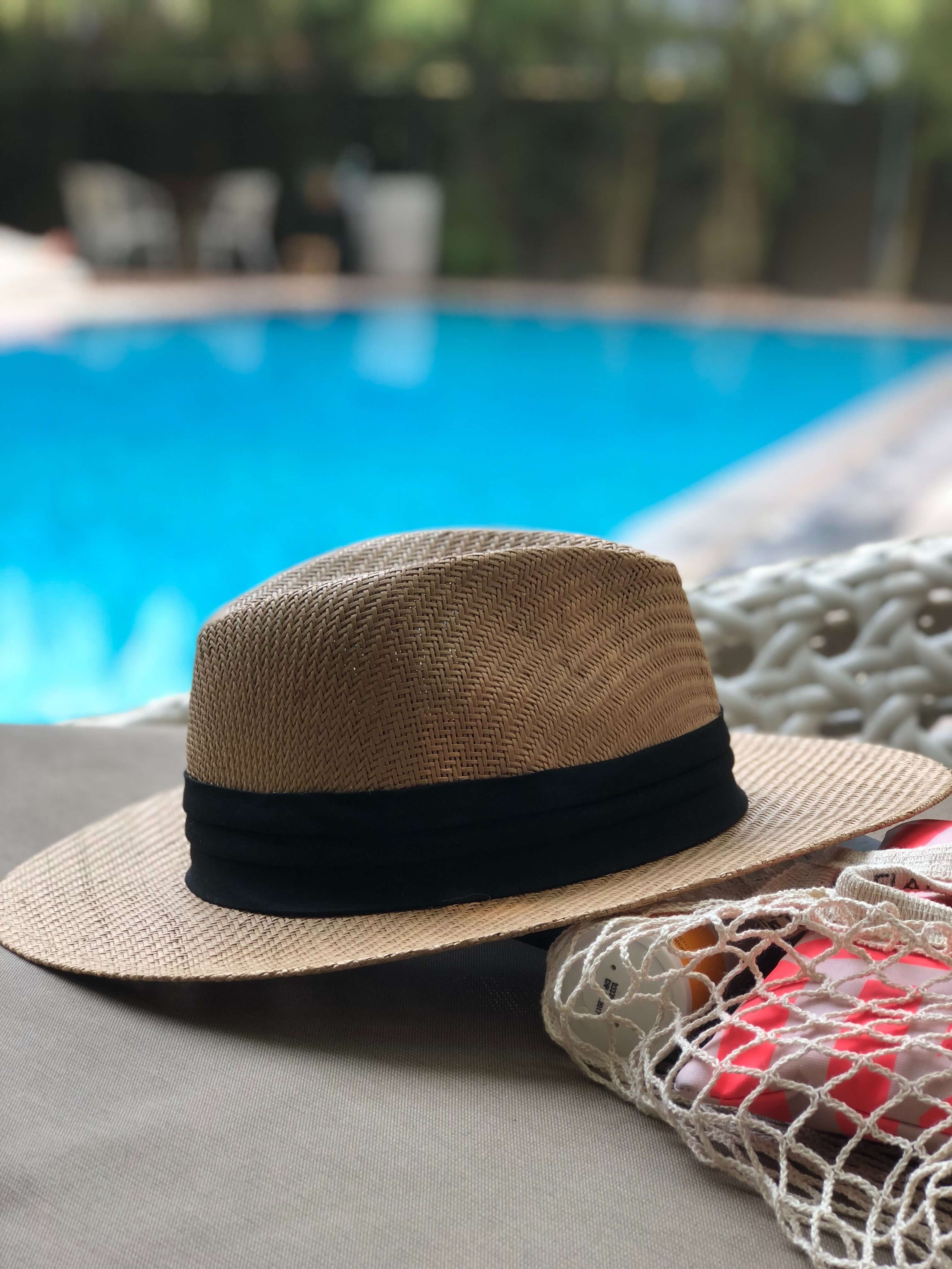 Hat laying poolside. Photo by Jude Stevens from Pexels